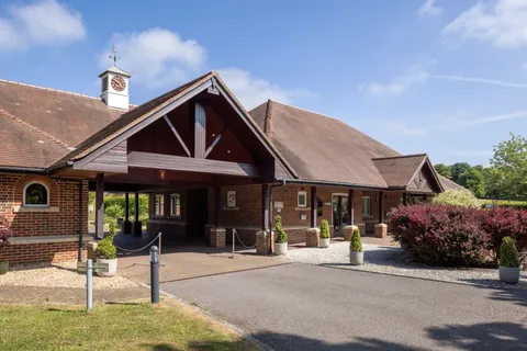 Basingstoke Crematorium — a brick building with a clock tower and a covered entrance porch, with clipped shrubs in pots either side of the drive
