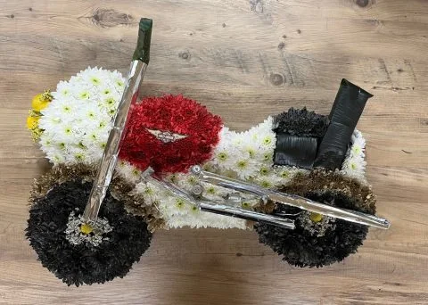A motorcycle made entirely of flowers — black chrysanthemum wheels, a red tank and a white body